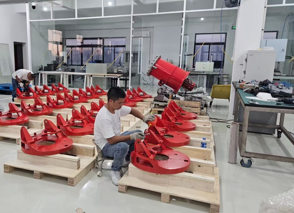 Technicians assembling red water mist turbine positioning bases on wooden supports in a workshop