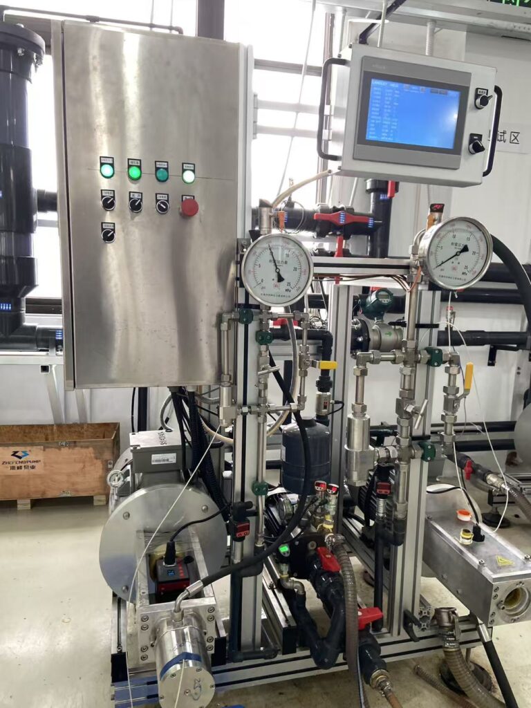High-pressure pump test rig with two pressure gauges, stainless steel piping and an operator control panel.