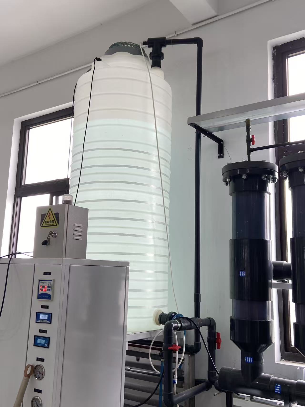 Water storage tank, treatment vessels and control instruments in an ultrapure water supply setup.